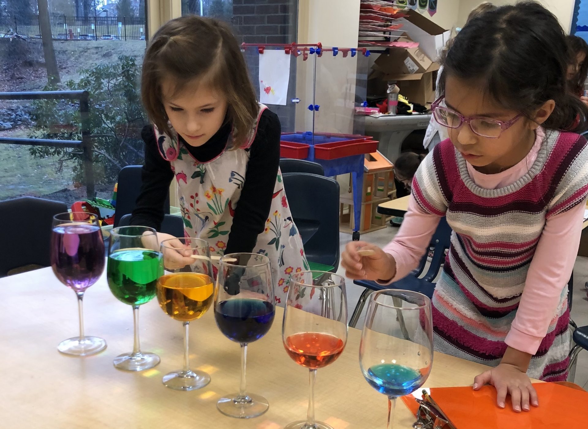 Two first grade girls work on a science project with colored water in class.
